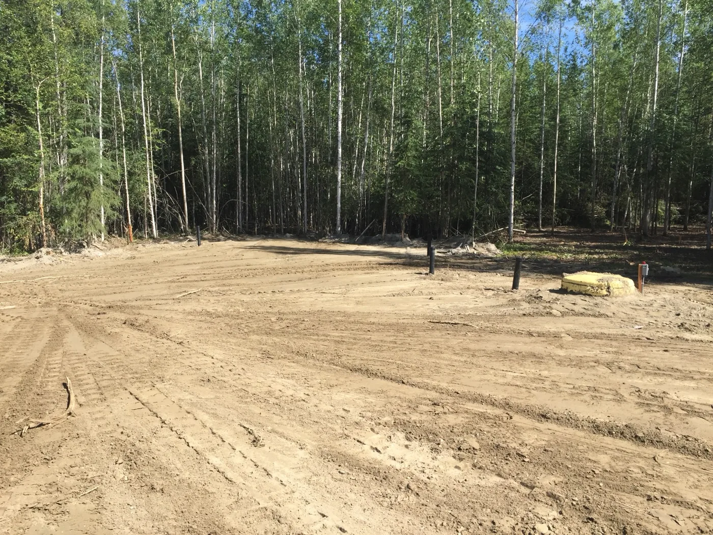 Cleared and graded open site bordered by trees