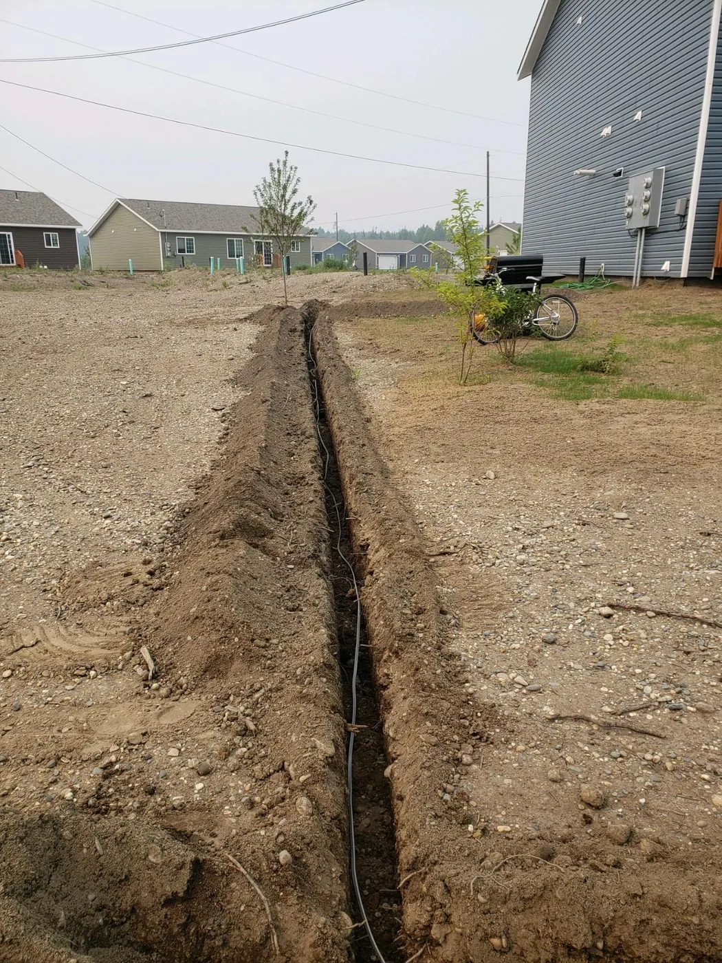 Narrow excavated trench alongside a building